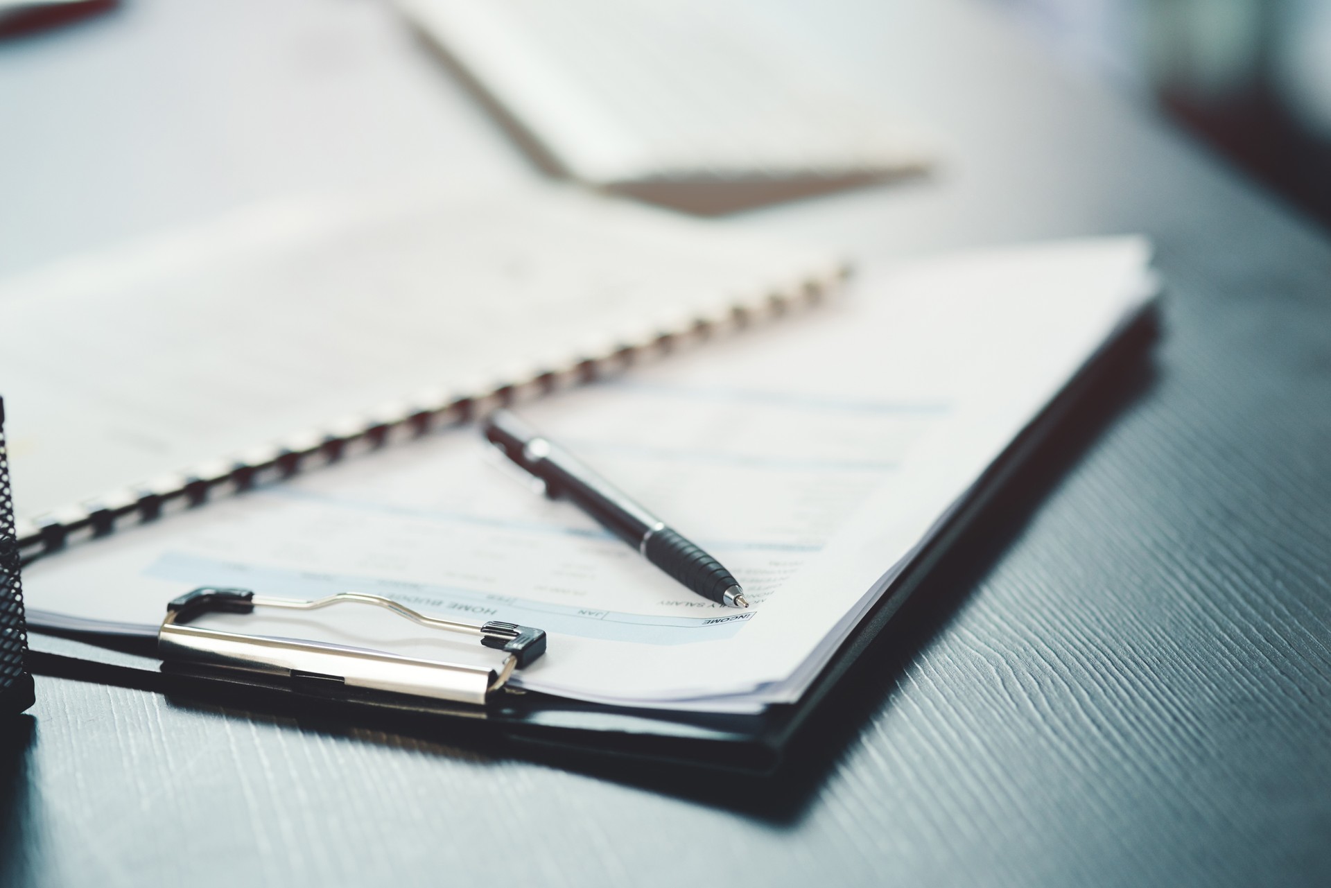 Shot of a notebook and pen on a desk in an office