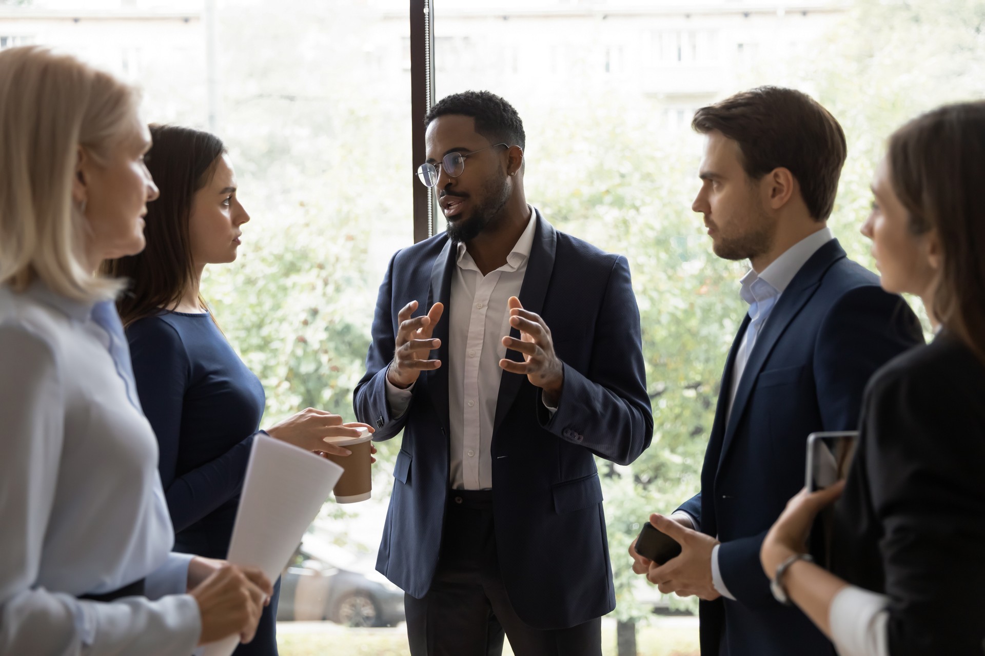 Confident African male leader telling diverse colleagues about new project